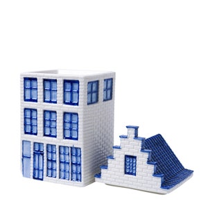 Könnte beinhalten: Ein weißes Keramikhaus mit blauen Verzierungen und Fenstern. Das Haus ist in zwei Abschnitte unterteilt, ein größeres Haupthaus und ein kleinerer Dachteil. Das Haus ist ein Dekorationsartikel.