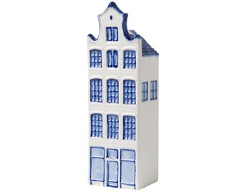 May include: A white ceramic miniature Dutch house with blue trim and windows. The house has a traditional gabled roof and multiple windows.