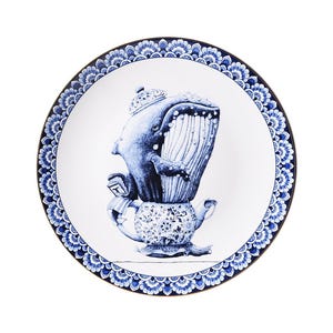 Op de afbeelding: Een blauw en wit porseleinen bord met een decoratieve rand heeft een grillige illustratie van een walvis die op een theepot zit. De walvis draagt een kroon en houdt een theekopje vast.