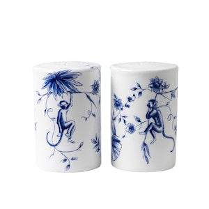 Op de afbeelding: Een set van twee witte keramische zout- en peperstrooiers met blauwe aap- en bloemmotieven.