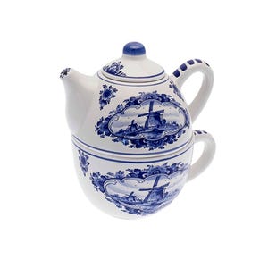 Op de afbeelding: Een witte keramische theepot en mok set met een blauw-wit Delfts blauw ontwerp met windmolens. De theepot heeft een deksel en een tuit. De mok heeft een handvat.