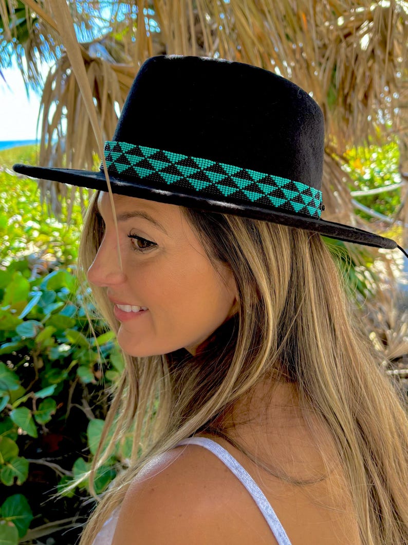 May include: A black fedora hat with a turquoise and black beaded band. The hat is worn by a person with long blonde hair.