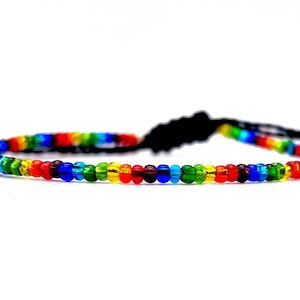 May include: A rainbow colored beaded bracelet with a black cord and adjustable knot closure.