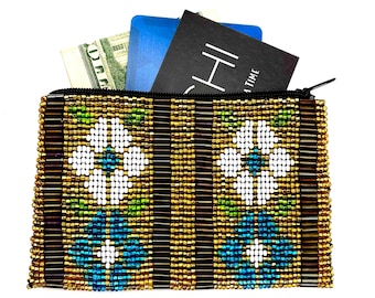 May include: A beaded zippered pouch with a gold, brown, blue, and white floral pattern. The pouch is open and has cash, a blue card, and a black book with the word "HIGH" visible inside.