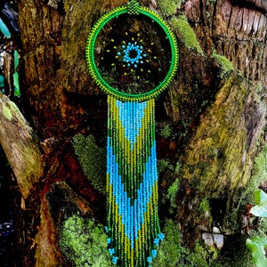 May include: A green and blue beaded dreamcatcher with a circular beaded design and a long beaded fringe hanging from the bottom.