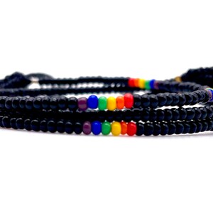 May include: A black beaded bracelet with a rainbow colored stripe of beads.