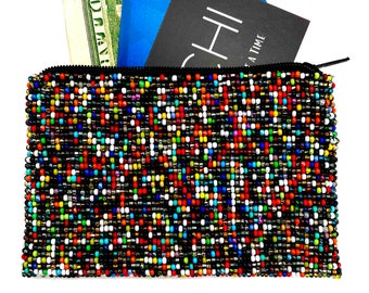 May include: A small, colorful beaded pouch with a zipper closure. The pouch is filled with cash and cards. The text "CH" is visible on a black card inside the pouch.