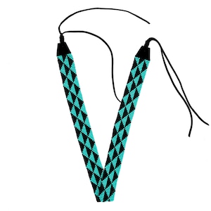 May include: A black beaded necklace with a turquoise geometric pattern. The necklace has two long ties that can be adjusted to fit.