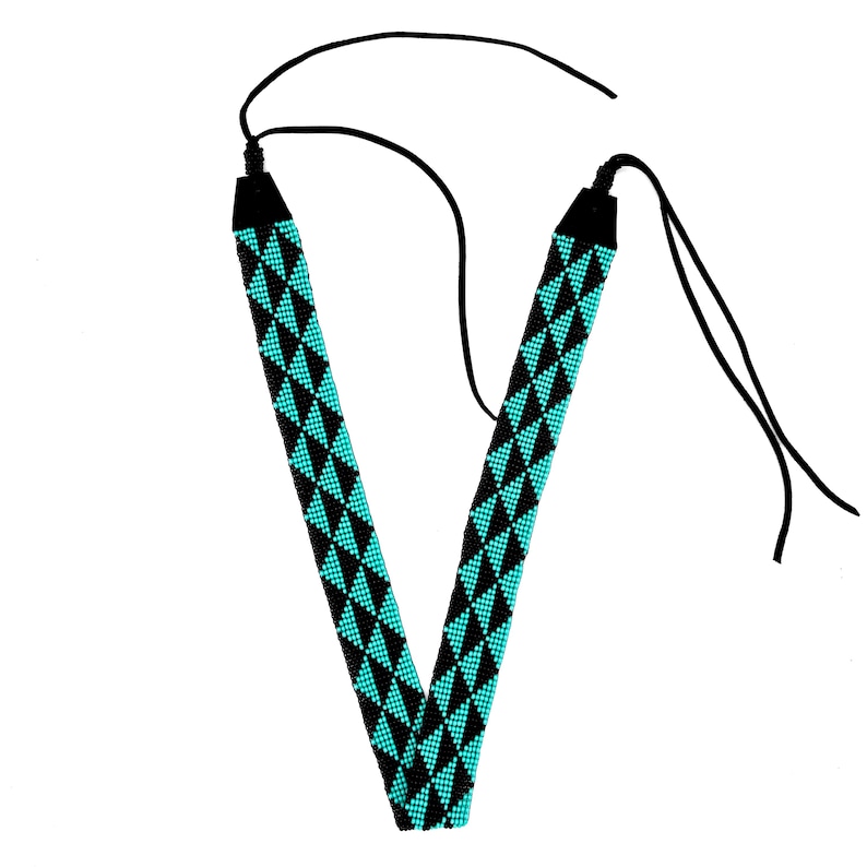 May include: A black beaded necklace with a turquoise geometric pattern. The necklace has two long ties that can be adjusted to fit.
