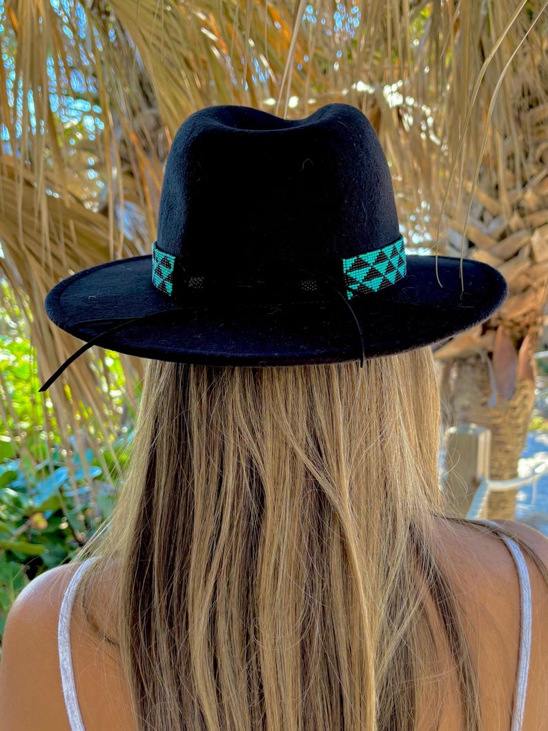 May include: A black fedora hat with a turquoise and black beaded band around the crown.