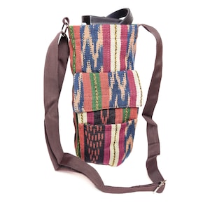 May include: A colorful woven fabric crossbody bag with a brown strap. The bag has multiple pockets and a unique pattern.