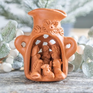 May include: A terracotta nativity scene with a clay manger and figures of Mary, Joseph, and the baby Jesus. The figures are surrounded by animals, including a donkey, a cow, and a sheep.