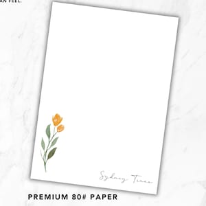 May include: A rectangular sheet of white 80# paper featuring a watercolor illustration of two orange flowers with green leaves in the lower left corner and the name Sydney Truss printed in a black script font in the lower right corner.