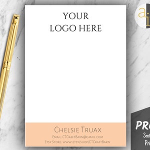 May include: A white notepad with the text "YOUR LOGO HERE" at the top and a peach-colored band at the bottom with the name "CHELSIE TRUAX". A gold pen rests on the marble surface. The notepad is a proof sent before printing.