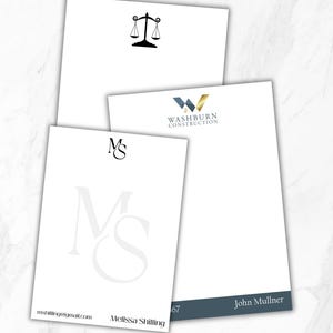 May include: Three white rectangular stationery sheets with custom branding. One features a black scale of justice icon, another displays the blue and gold Washburn Construction logo, and the third shows the initials MS with the name Melissa Shilling.