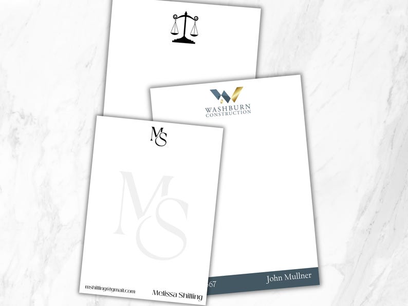 May include: Three white rectangular stationery sheets with custom branding. One features a black scale of justice icon, another displays the blue and gold Washburn Construction logo, and the third shows the initials MS with the name Melissa Shilling.