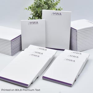May include: A collection of white rectangular notepads with purple bottom edges, each featuring the black text HWA Heather White Accounting and a magnifying glass icon. The paper is printed on 80LB premium text paper stock.