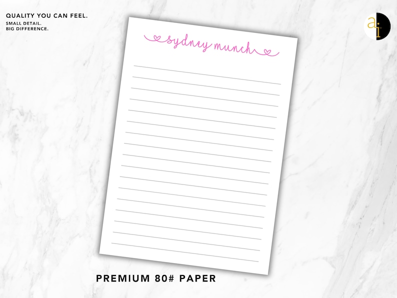 May include: A white notepad sheet featuring horizontal black lines and the pink cursive text "sydney munch" flanked by two small heart icons at the top. The paper is labelled as premium 80lb paper with the text "QUALITY YOU CAN FEEL. SMALL DETAIL. BIG DIFFERENCE."