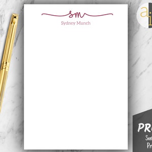 May include: White stationery with a gold pen on a marble surface. The stationery features a burgundy design with the initials "sm" and the name "Sydney Munch". A black and white logo is in the upper right corner. A "PROOF" stamp is in the lower right corner.