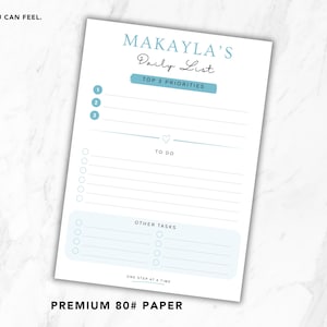 May include: A white paper daily list titled "Makayla's Daily List" with light blue accents. The list includes sections for top priorities, to-do items, and other tasks. The text "Premium 80# Paper" is at the bottom.