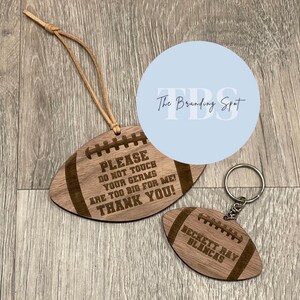 May include: Two wooden football-shaped items. One is a hanging ornament with the text "PLEASE DO NOT TOUCH YOUR GERMS ARE TOO BIG FOR ME! THANK YOU!". The other is a keychain with the name "BECKETT RAY BLANCAS".