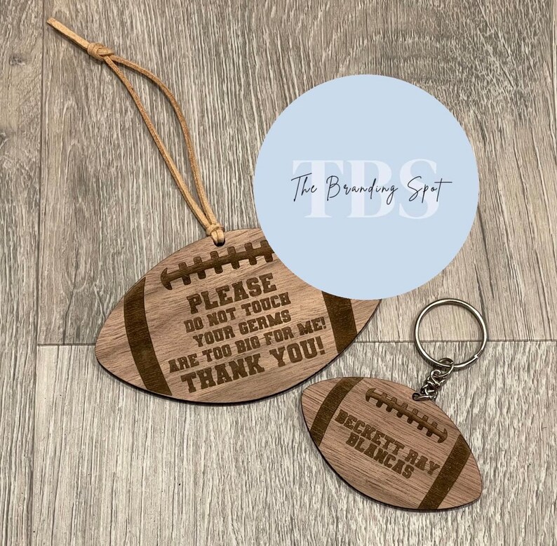 May include: Two wooden football-shaped items. One is a hanging ornament with the text "PLEASE DO NOT TOUCH YOUR GERMS ARE TOO BIG FOR ME! THANK YOU!". The other is a keychain with the name "BECKETT RAY BLANCAS".