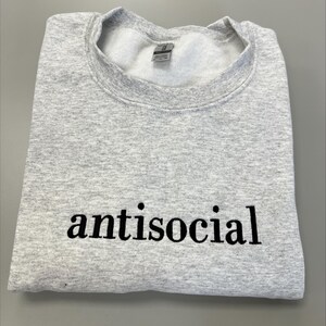 May include: A gray sweatshirt with the word "antisocial" printed in black on the front.