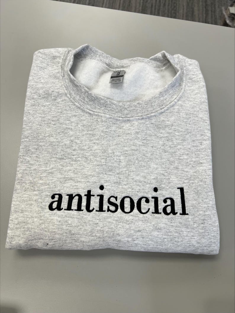 May include: A gray sweatshirt with the word "antisocial" printed in black on the front.