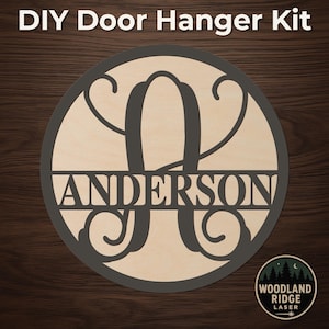 May include: DIY door hanger kit with the name "Anderson" and a large letter "A" in a circular design. The design is laser cut from wood and has a dark gray border. The text "DIY Door Hanger Kit" is at the top.