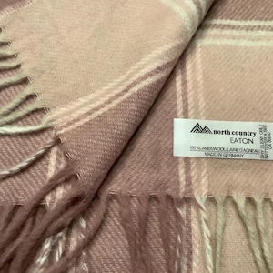 May include: A pink and white checked scarf with a fringed trim. The label reads "north country EATON 100% LAMBSWOOL/LAINE DAGNEAU MADE IN GERMANY".