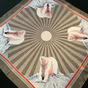Op de afbeelding: Vierkante zijden sjaal met een ijsbeer- en zeehondenontwerp. De sjaal heeft een centraal zonnestralenpatroon met een witte cirkel in het midden. De rand is grijs met een rode streep.