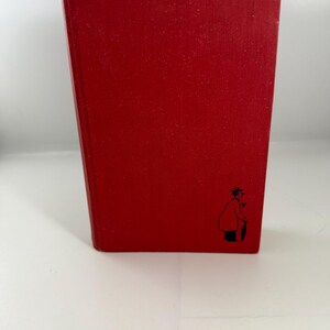 May include: A red hardcover book with a black and white illustration of a person on the front cover.