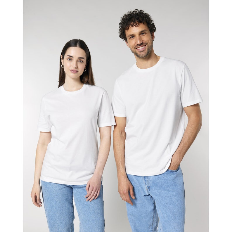 Może przedstawiać: Dwie osoby ubrane w białe t-shirty z okrągłym dekoltem i jasnoniebieskie dżinsy. T-shirty mają kr&oacute;tkie rękawy i prosty kr&oacute;j. Dżinsy są z jasnego denimu. Tło jest jednolicie białe.