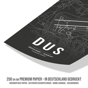 Puede incluir: Un mapa en blanco y negro de D&uuml;sseldorf, Alemania, con el nombre de la ciudad y las coordenadas impresas en blanco. El texto "250 gr/qm Premium Papier - In Deutschland Gedruckt" est&aacute; impreso en la parte inferior del mapa. El texto "Hochwertiges Papier - Gestochen Scharfer Druck - Grobe Auswahl - Geschenkidee" est&aacute; impreso debajo de la primera l&iacute;nea de texto.