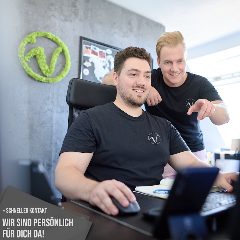 Puede incluir: Dos personas en una oficina moderna. Una persona est&aacute; sentada en un escritorio usando una computadora, mientras que la otra persona est&aacute; de pie detr&aacute;s de ella, apuntando a la pantalla de la computadora. El texto en la pantalla dice "Schneller Kontakt. Wir sind pers&ouml;nlich f&uuml;r dich da!"