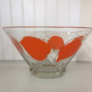May include: A clear glass bowl with a wide rim and a flared base. The bowl has a geometric design of orange and gold shapes.