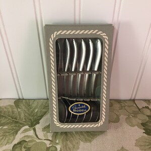 May include: A set of six silver teaspoons in a gray box with a blue and white label that reads "Svensk Modell".