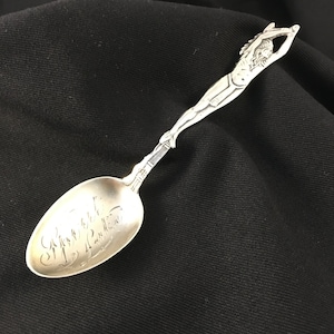 Peut inclure: Une cuillère en argent avec une figurine de femme sur le manche. Le bol de la cuillère est gravé des mots "The Mermaid Tavern".