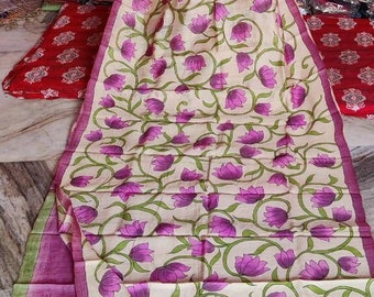 May include: A cream-colored silk saree with a pink floral print. The saree has a pink border and is draped over a mannequin.