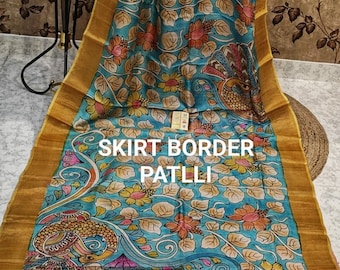 May include: A blue and gold saree with a floral print and a peacock design. The saree has a gold border with a purple and gold stripe. The text "SKIRT BORDER PATLLI" is visible on the saree. The text "OnePlus 11 | Kolkata" is visible in the bottom right corner of the image.