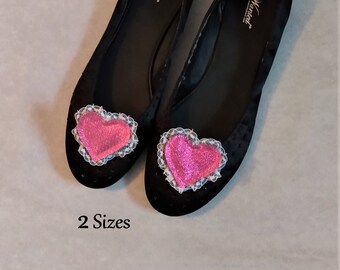 May include: A pair of black ballet flats with a pink heart and white lace trim. The flats are labeled "Manet" on the inside.