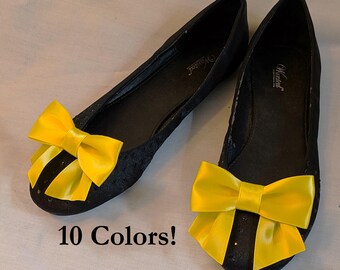 May include: Pair of black flats with yellow satin bows. The shoes have a small hole pattern and the text "Wanted" is visible on the inside of one shoe. The text "10 Colors!" is visible below the shoes.