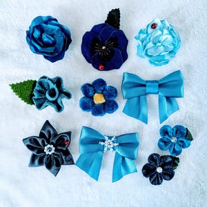 以下が含まれることがあります： サテンのバラ、ベルベットのパンジー、クリスタル付きの布製リボン、小さな花のアップリケなど、9種類の青いヘアアクセサリーのコレクション。明るいシアンから深いネイビーまで、さまざまな青の色合いで構成されています。