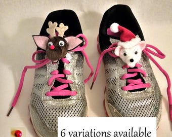 May include: A pair of silver glitter sneakers with pink laces. One shoe has a reindeer shoe charm and the other has a white dog wearing a Santa hat shoe charm.  "6 variations available" is written below the shoes.