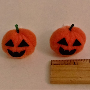 Pode incluir: Duas pequenas ab&oacute;boras de feltro laranja com rostos de feltro preto. As ab&oacute;boras t&ecirc;m um di&acirc;metro de aproximadamente 2,5 cm.