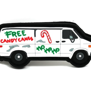 May include: White van with black trim and a black border. The van has green and red graffiti that says "FREE CANDY CANES" and "HO HO HO". There is a red and white candy cane drawn on the side of the van.