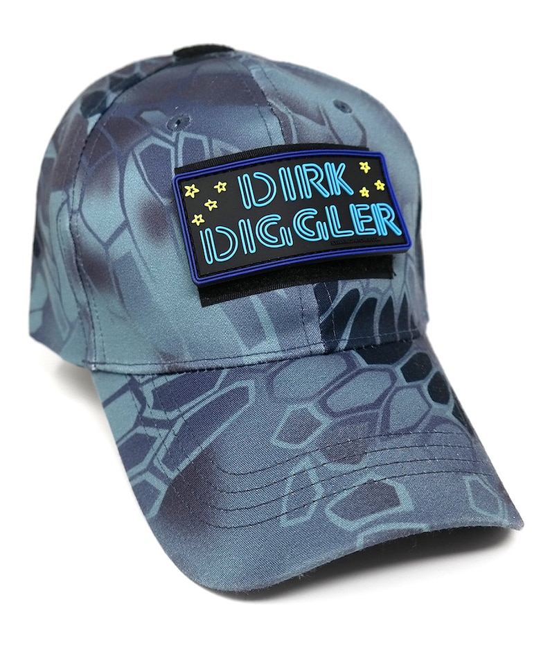 May include: A blue camouflage baseball cap with a black patch that says "DIRK DIGGLER" in blue neon letters with yellow stars.