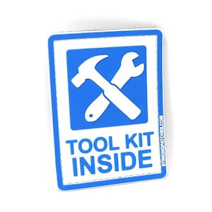 Könnte beinhalten: Ein weiß-blauer Patch mit einem weißen Hammer und Schraubenschlüssel, die sich auf einem blauen Hintergrund kreuzen. Der Text "TOOL KIT INSIDE" ist in weiß unter den Werkzeugen aufgedruckt.