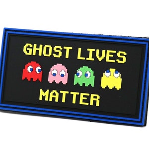 Peut inclure: Un patch noir et bleu avec le texte "Ghost Lives Matter" en lettres jaunes pixelisées. Quatre fantômes pixelisés sont représentés en rouge, rose, vert et jaune.
