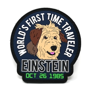 May include: A blue and black circular patch with a white border. The patch features a cartoon dog with brown ears and the text "WORLD'S FIRST TIME TRAVELER EINSTEIN OCT 26 1985".